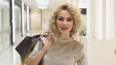 漂亮的女孩带着购物袋转过身来，笑成了照相机。 年轻女子在商场卖东西